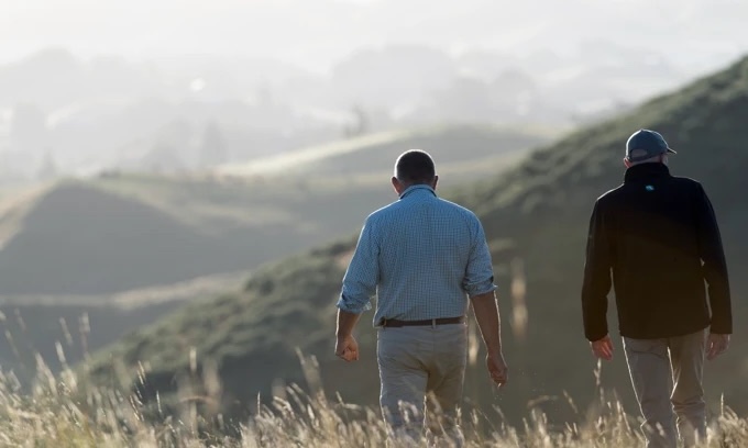 Advisor and farmer walking together on a New Zealand hill farm
